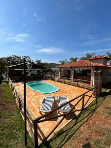 a patio with two chairs and a swimming pool at Pousada Estância Mineira in Guapé