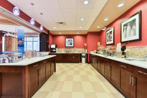 a large kitchen with red walls and wooden cabinets at Hampton Inn Corning/Painted Post in Painted Post