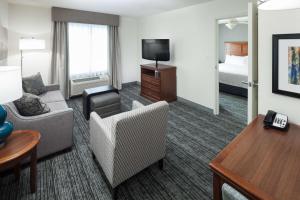 a hotel room with a couch and a chair and a television at Homewood Suites by Hilton El Paso Airport in El Paso