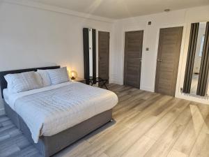 a white bedroom with a bed and wooden floors at Penthouse Studio by Regent's Park/Euston in London
