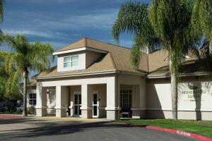 a building with palm trees in front of it at Homewood Suites by Hilton Fresno Airport/Clovis in Clovis