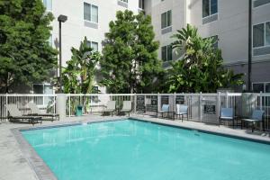 a swimming pool with chairs and a building at Homewood Suites by Hilton Fresno Airport/Clovis in Clovis