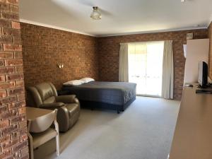 ein Schlafzimmer mit einem Bett, einem Sofa und einem Stuhl in der Unterkunft Settlement Motor Inn in Deniliquin