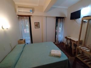 Hotel Manzanares Plaza في بوينس آيرس: غرفة نوم بسرير اخضر ومكتب ونافذة