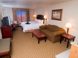 a hotel room with a bed and a couch at Hampton Inn & Suites Farmington in Farmington