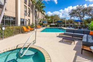 a swimming pool with lounge chairs and a hotel at Hampton Inn Commercial Boulevard-Fort Lauderdale in Tamarac