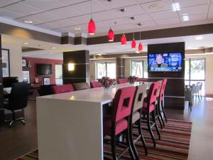 Hampton Inn Fort Myers-Airport & I-75 في فورت مايرز: مطعم مع بار وكراسي وردية وتلفزيون