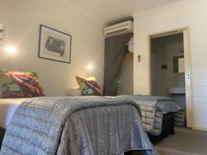 a hotel room with two beds and a bathroom at Kookaburra Motel Yungaburra in Yungaburra