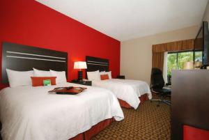 Hampton Inn Fort Myers-Airport & I-75 في فورت مايرز: سريرين في غرفة الفندق بجدران حمراء