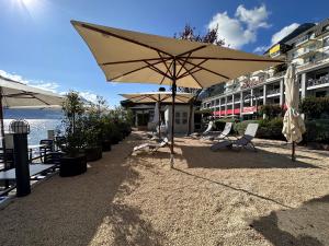 eine Terrasse mit Stühlen und einem Sonnenschirm neben einem Gebäude in der Unterkunft Seehotel Riviera at Lake Lucerne in Gersau