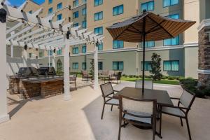 a patio with a table and chairs and an umbrella at Homewood Suites by Hilton Ft. Worth-North at Fossil Creek in Fort Worth