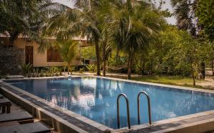 a swimming pool in a resort with palm trees at C Beyond Nilaveli in Nilaveli