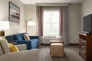 a living room with a blue couch and a tv at Homewood Suites Fort Wayne in Fort Wayne