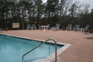 una piscina con sillas, una mesa y un cartel en Hampton Inn Kilgore, en Kilgore