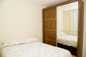 ein Schlafzimmer mit einem Spiegel neben einem Bett in der Unterkunft Conforto & tranquilidade in Rio das Ostras