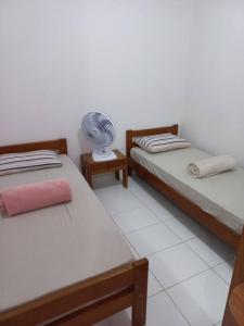 a room with two beds and a fan on a table at Minha Casa Padrão em Bonito in Bonito