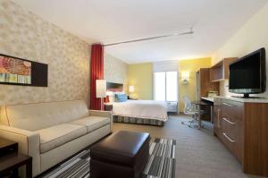 ビロクシにあるHome2 Suites by Hilton Biloxi/North/D'Ibervilleのソファ、ベッド、テレビが備わるホテルルームです。