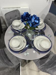 una mesa con platos y un jarrón de flores azules en Blue Madison en Aldershot