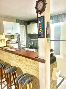 a kitchen with a counter with stools and a clock at Praia de Geribá e piscina para sua família! in Búzios