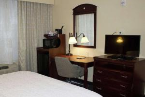 a hotel room with a bed and a desk with a television at Hampton Inn Gallipolis in Gallipolis