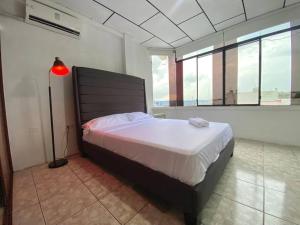 ein Schlafzimmer mit einem Bett und einer Lampe in einem Zimmer in der Unterkunft Moderno, grande, amplia vista, parqueo in Machala