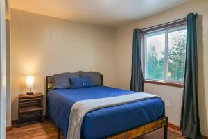 a bedroom with a blue bed and a window at Pinetree Lodge: Hot Tub Fire Pit in Athol
