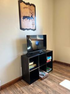 a room with a black entertainment center with a flat screen tv at Pinetree Lodge: Hot Tub Fire Pit in Athol