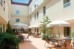 un patio extérieur avec des tables, des chaises et des parasols dans l'établissement Hampton Inn & Suites Hershey, à Hershey