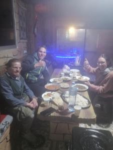 grupa ludzi siedzących przy stole z jedzeniem w obiekcie Dana Nabil Ecu Camp House - Main Gate Dana nature reserve w mieście Dana