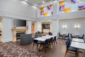 Hampton Inn and Suites Hartford/Farmington في فارمينغتون: لوبي به طاولات وكراسي وموقد