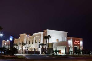a large white building with palm trees in front of it at Hampton Inn & Suites Harlingen in Harlingen