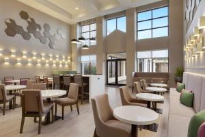 a restaurant with tables and chairs and windows at Hampton Inn & Suites Houston-Cypress Station in Westfield