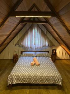 1 dormitorio con 1 cama con 2 zapatillas en Cabana Centenária com Ofurô en Rodeio Doze