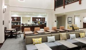 a lobby with a couch and tables and a kitchen at Homewood Suites by Hilton Houston Stafford Sugar Land in Stafford