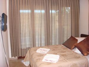 a bedroom with a bed with two towels on it at Suites Pipa Beleza Spa Resort in Pipa