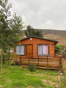 a log cabin with a fence and a house at La Serena Cabaña de campo entre cactus y colibríes in La Serena