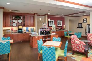 a kitchen with wooden cabinets and blue chairs and a table at Hampton Inn Jacksonville in Jacksonville