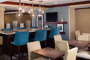 a restaurant with blue chairs and a bar with a tv at Hampton Inn Long Island/Islandia in Islandia