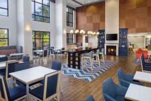 a lobby with tables and chairs and a fireplace at Hampton Inn by Hilton Garden City Long Island in Garden City