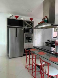 a kitchen with a stainless steel refrigerator and red chairs at Casa em Guarujá-Jardim Acapulco in Guarujá