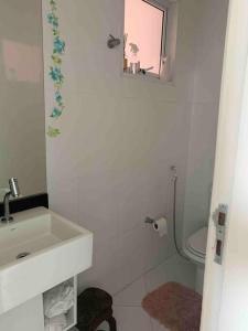 a white bathroom with a sink and a toilet at Casa em Guarujá-Jardim Acapulco in Guarujá