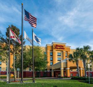 a hotel with three american flags in front of it at Hampton Inn & Suites Jacksonville South - Bartram Park in Jacksonville
