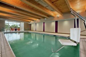 a swimming pool with a chair in a building at Home2 Suites by Hilton Jacksonville, NC in Jacksonville