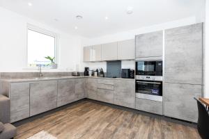 cocina con electrodomésticos de acero inoxidable y suelo de madera en New 2BR wBalcony 1 min Ponders End Train, Enfield en Ponders End