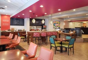 a restaurant with tables and chairs and a bar at Hampton Inn Johnstown in Geistown