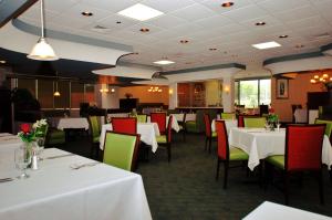 uma sala de jantar com mesas brancas e cadeiras verdes em DoubleTree by Hilton Fayetteville em Fayetteville