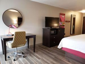 a hotel room with a bed and a desk and a mirror at Hampton Inn Johnstown in Geistown
