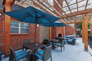 un patio con mesas, sillas y sombrillas en Homewood Suites by Hilton Greensboro, en Greensboro