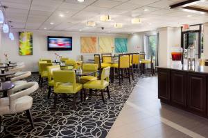 a restaurant with yellow chairs and tables and a bar at DoubleTree by Hilton Springdale in Springdale