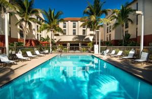 a swimming pool at a hotel with chairs and palm trees at Hampton Inn & Suites Fort Myers Beach/Sanibel Gateway in Fort Myers Beach